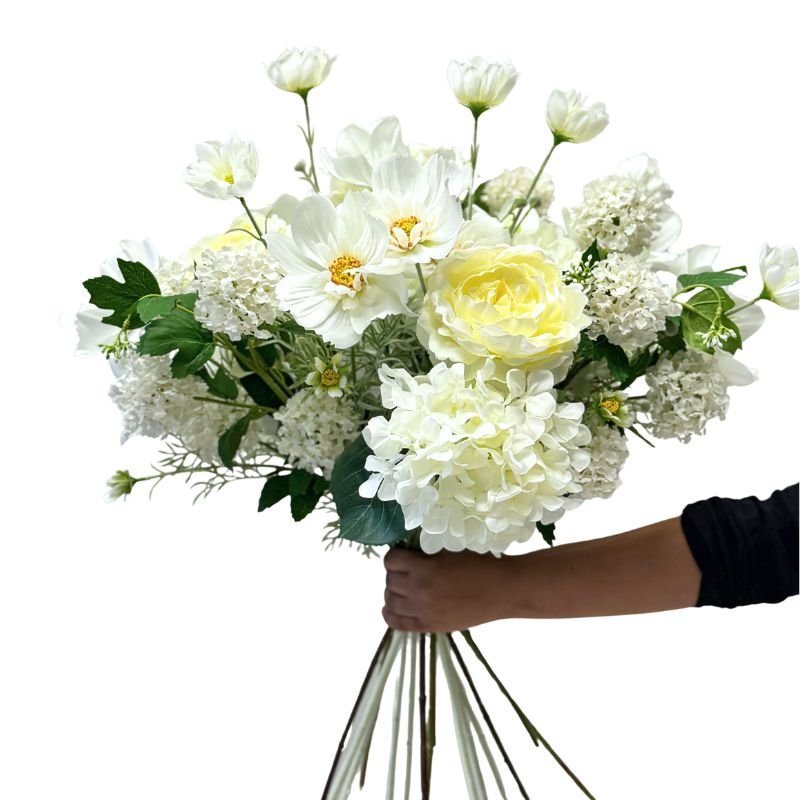 Bouquet of white and yellow flowers held by a person against a white background