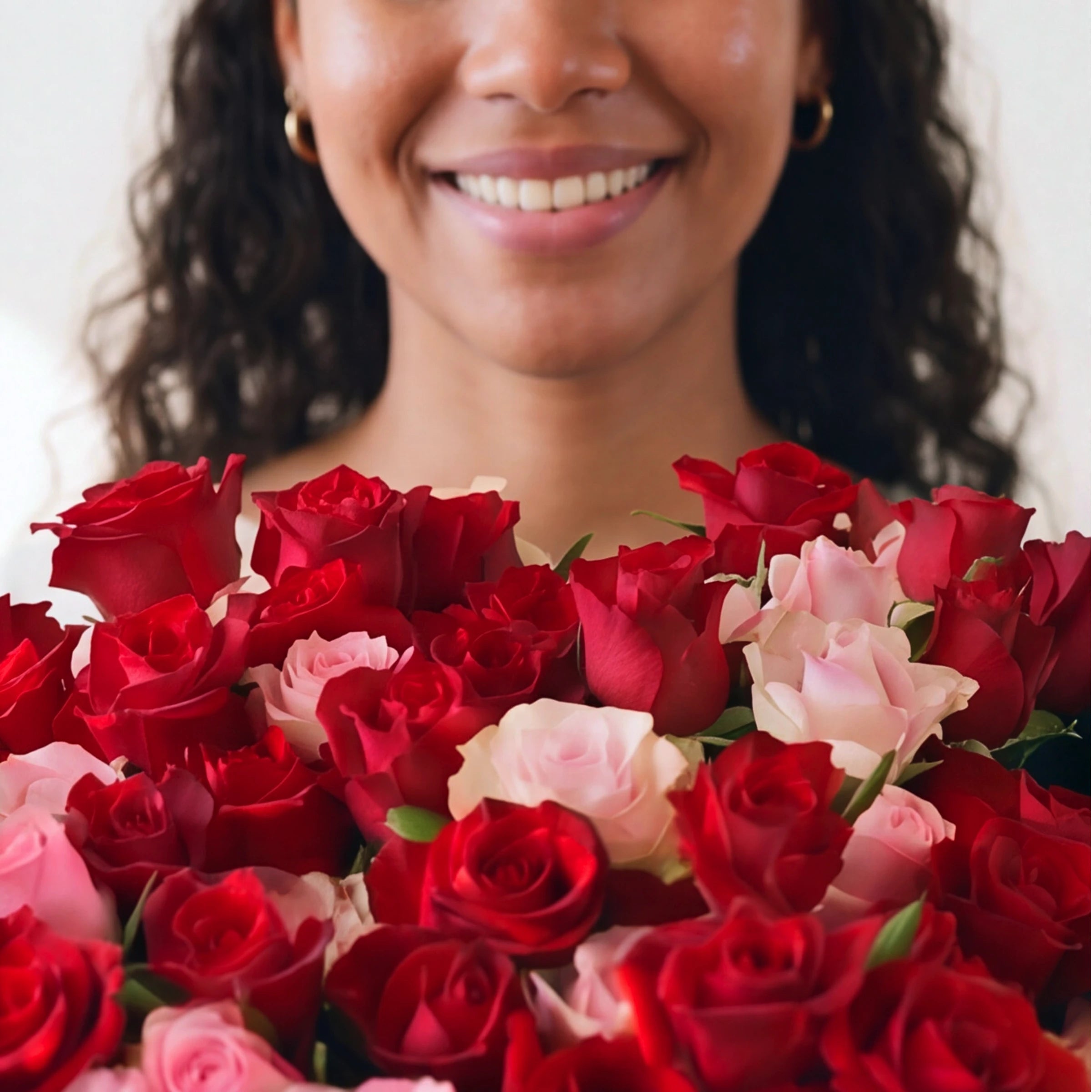 Smiling woman behind a huge Fabulous Flowers bouquet of red and pink roses
