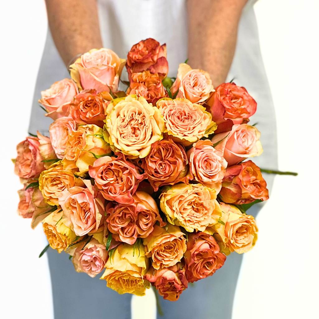 Bouquet of multicolored roses held by a person with a blurred background