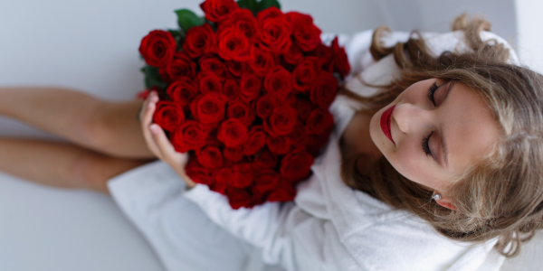 Woman holding a large bouquet of red roses against a white background