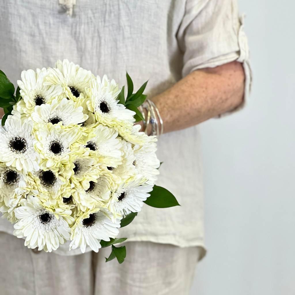 20 Whispering White Gerbera Bouquet Stems being held by a florist - Fabulous Flowers