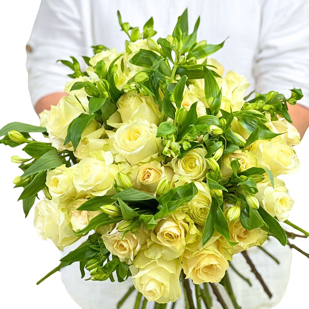 Bouquet of yellow roses with greenery held by a person wearing a white shirt.
