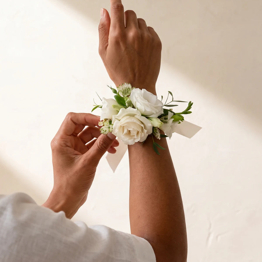 Woman adjusting a white rose wrist corsage on her raised wrist, Fabulous Flowers South Africa