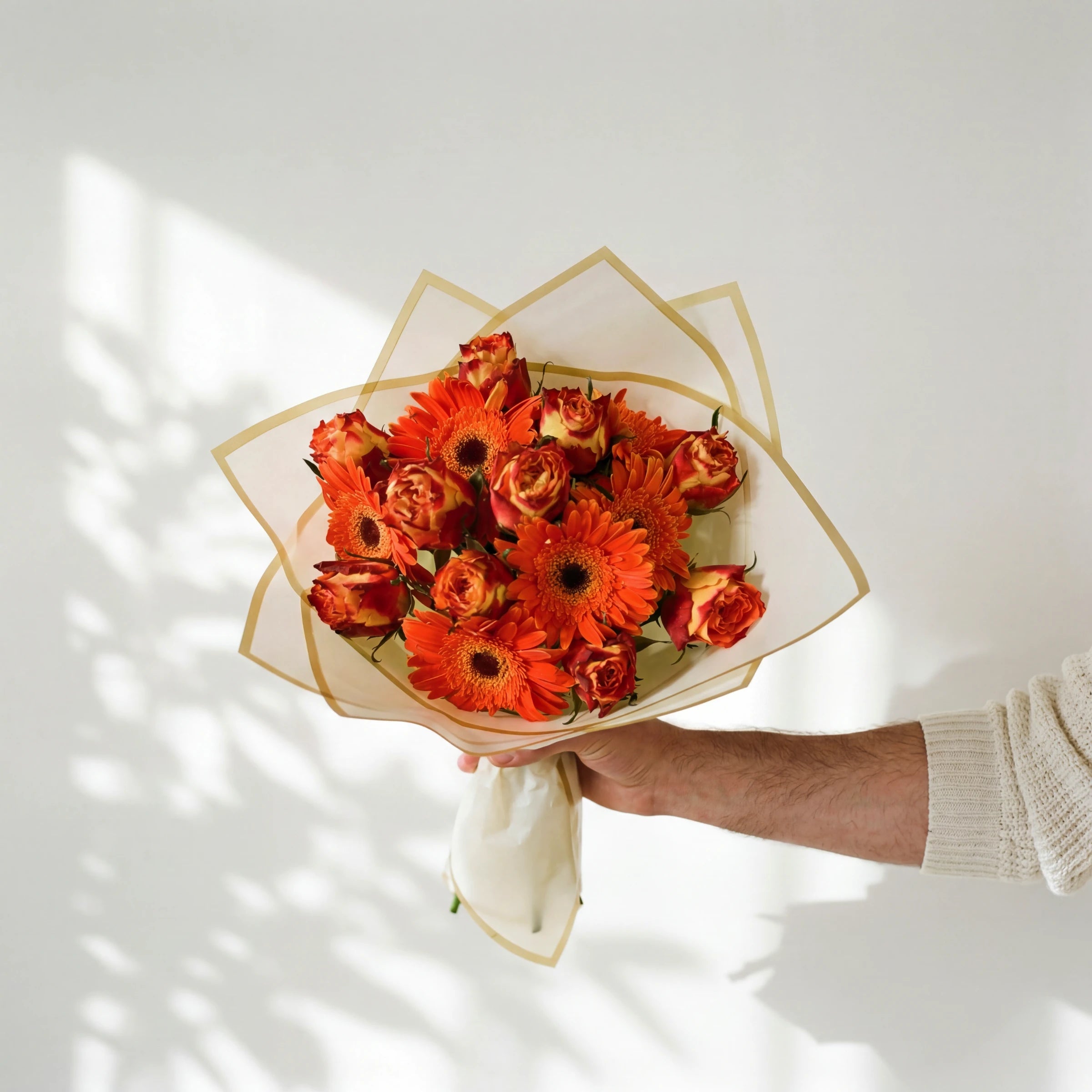 Wildfire bouquet of orange gerberas and bi-colour orange and gold roses in a cream and gold wrap, held by Fabulous Flowers