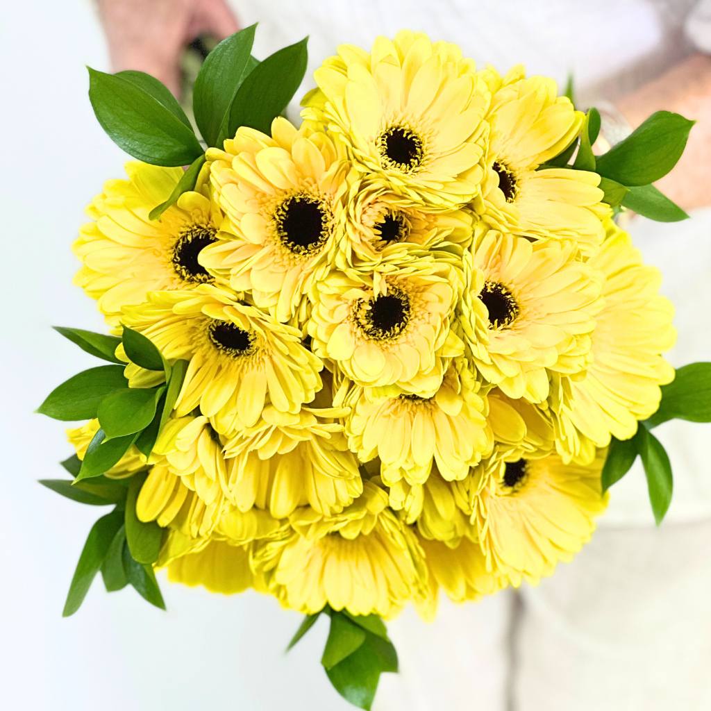 Bouquet of yellow flowers with green leaves on a white background