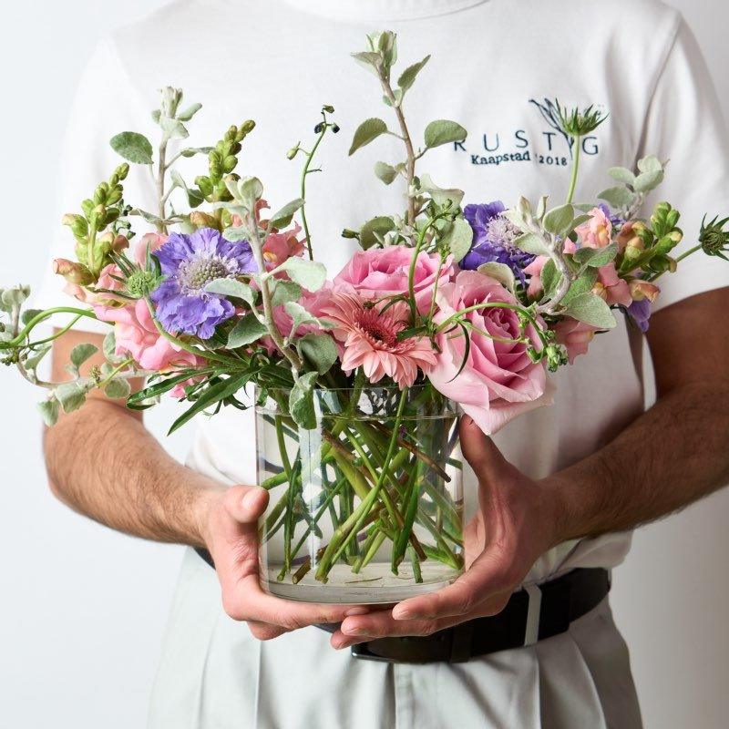 Person holding a vase of flowers with 'Krustig' branding in the background