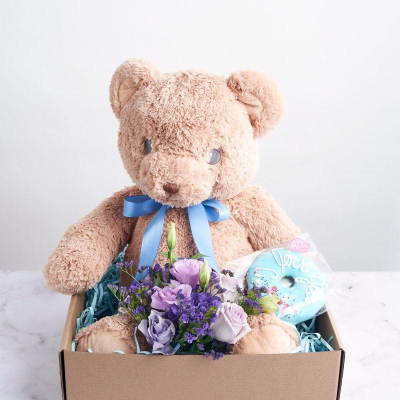 Brown teddy bear toy with lavender and blue flowers and a delicious blue donut | Order A Prince was born from Fabulous Flowers and Gifts