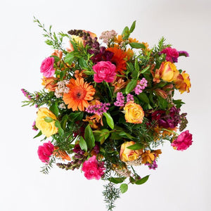 Close up of the First Spring Blooms flower arrangement including orange gerberas, yellow roses, pink ranunculus and greenery from Fabulous Flowers and Gifts