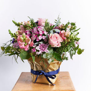 Flower arrangement in container with Alstromeria, pink roses,  purple statice, pink snapdragons, sweet william and wild greenery