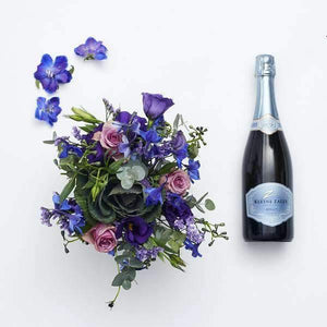 top shot of blue and lilac flower arrangement with kleine zalze champage